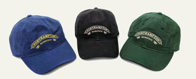 Three baseball caps in blue, black, and green with 'Northampton' embroidered design by small victories