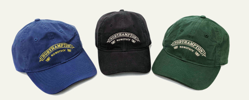Three baseball caps in blue, black, and green with &