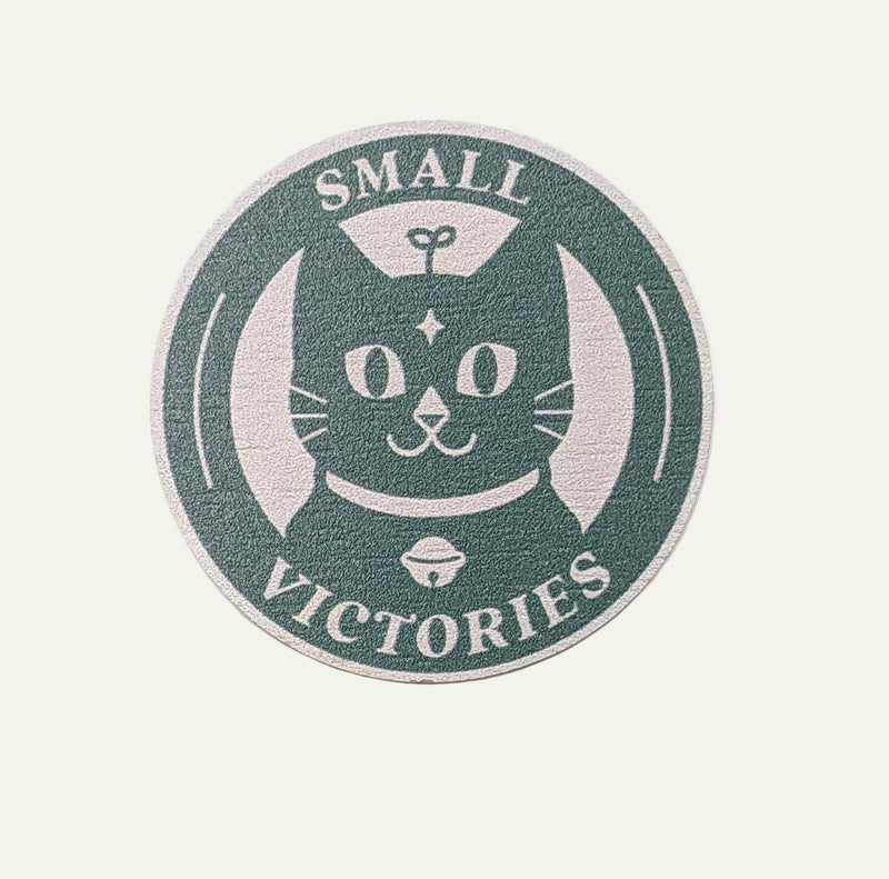 Circular wooden pin with a cat illustration and &